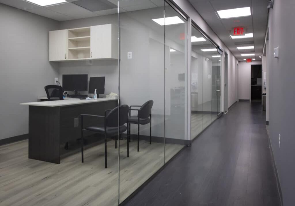 Modern orthodontic office interior with glass-walled reception area and dental workspace setup.
