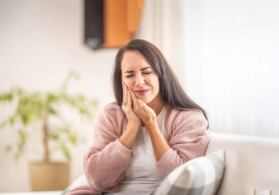 Smiling woman relaxing on couch at home in casual pink cardigan.