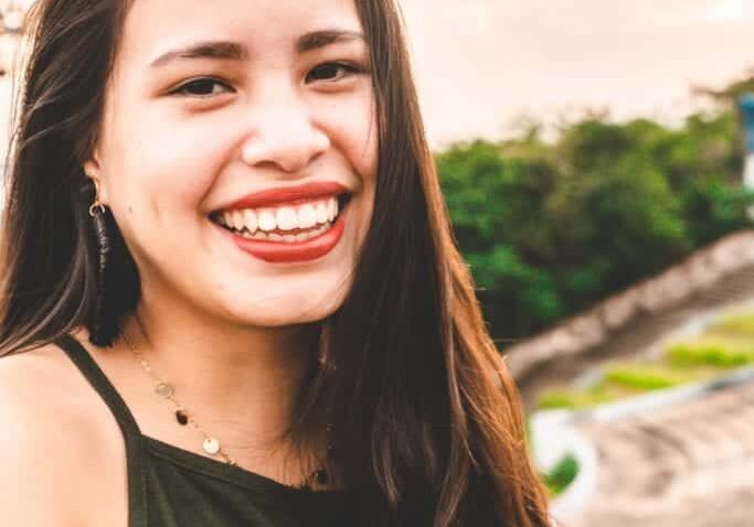 smiling woman with sn in background